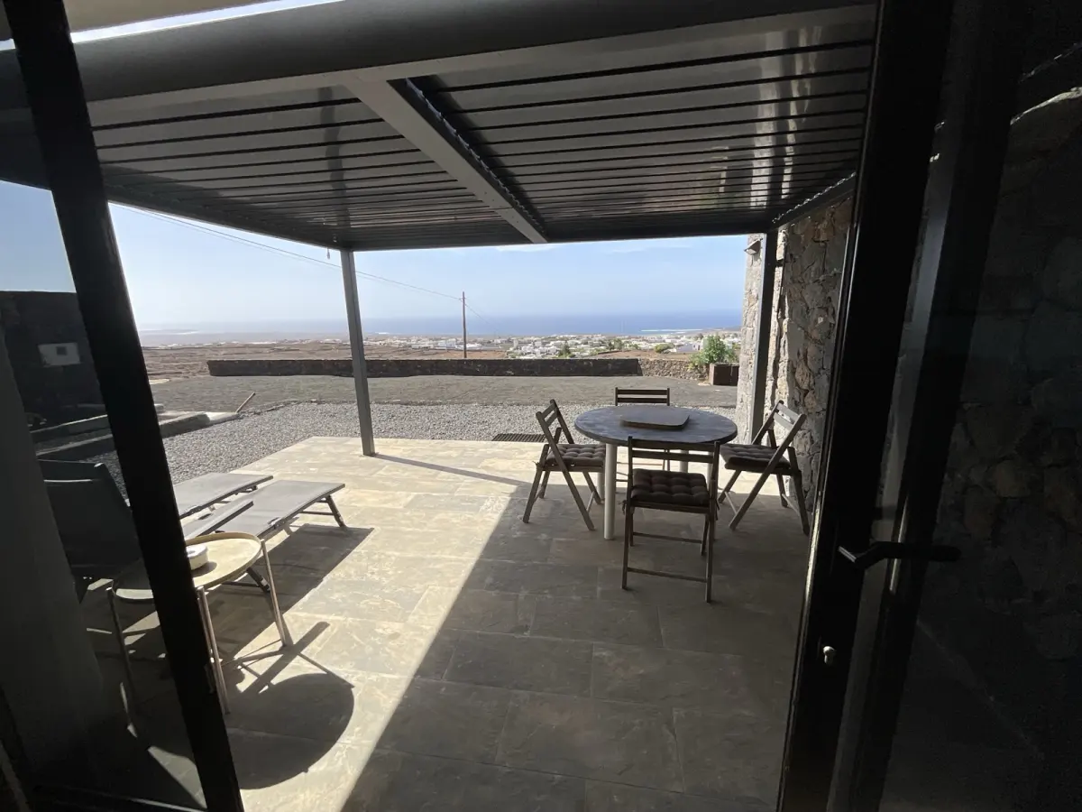 Terrasse du F1 sous pergola, table et transats face à l'océan